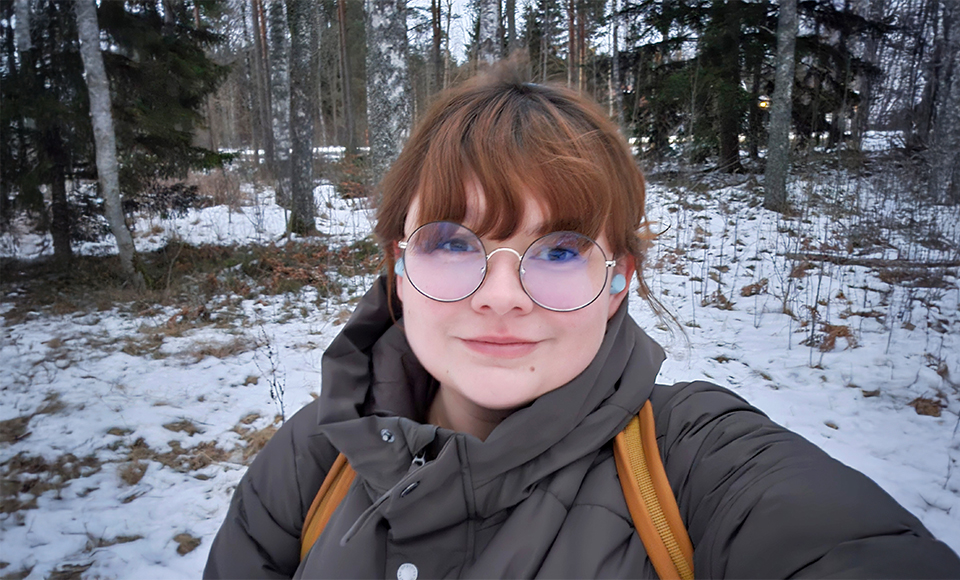 Selfie av Erica Bahr. I bakgrunden syns träd och på marken ligger snö.
