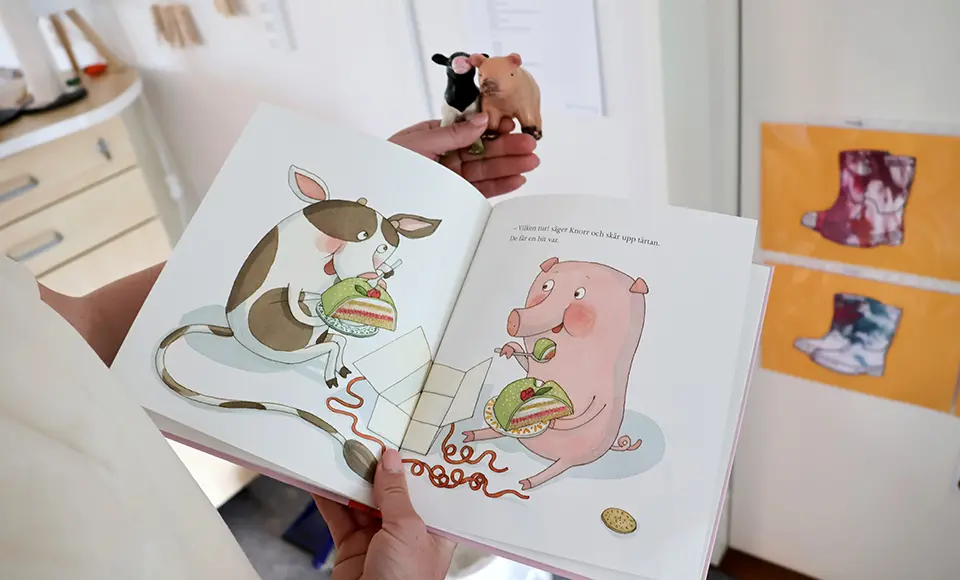 En uppslagen bilderbok med en ko och en gris visas tillsammans med små djurfigurer.