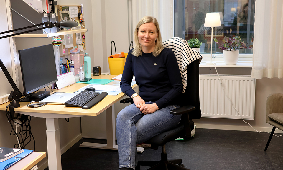 Malin Linnåsen sitter vid ett skrivbord och tittar in i kameran.