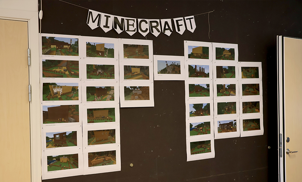 Utskrivna bilder på elevernas Minecrafthus är upphängda på en vägg.