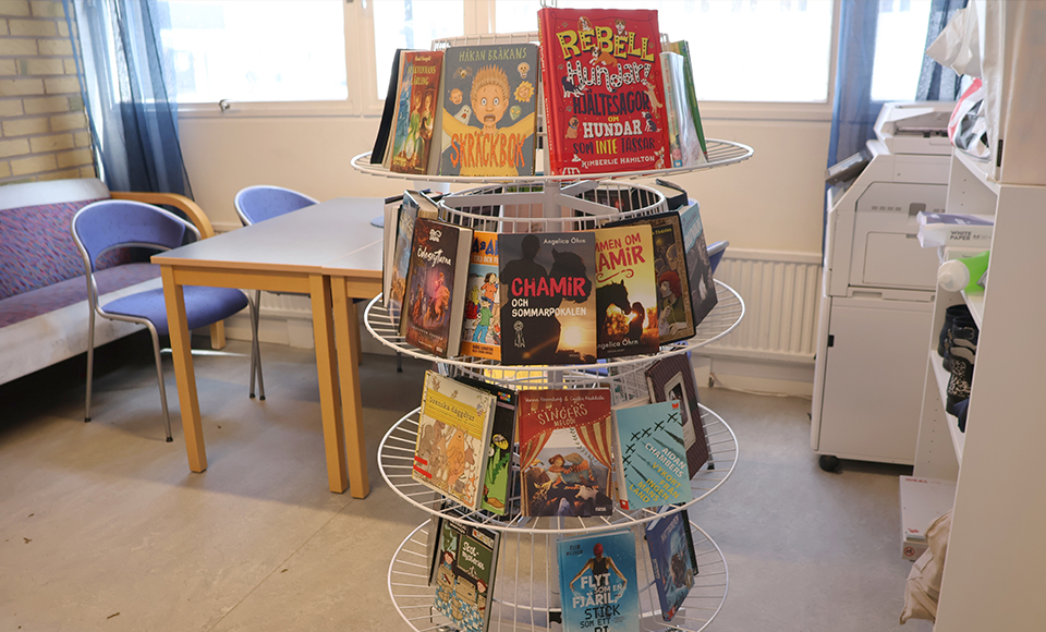Bilden visar en ställning med böcker som står i en skolkorridor.