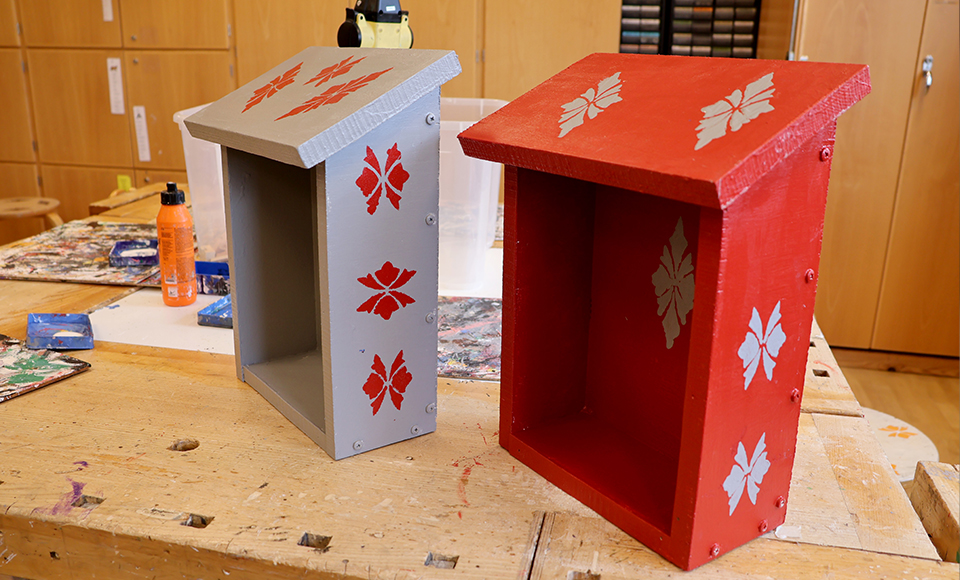 Bilden visar två lådor i trä med öppningsbart lock.