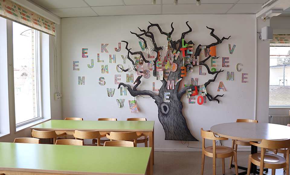 Ett målat träd uppsatt på en vägg med bokstäver runt.