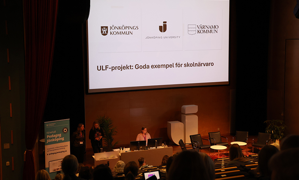 En konferensscen där tre personer står. En pratar och i bakgrunden syns en presentation med texten ULF-projekt: Goda exempel för skolnärvaro