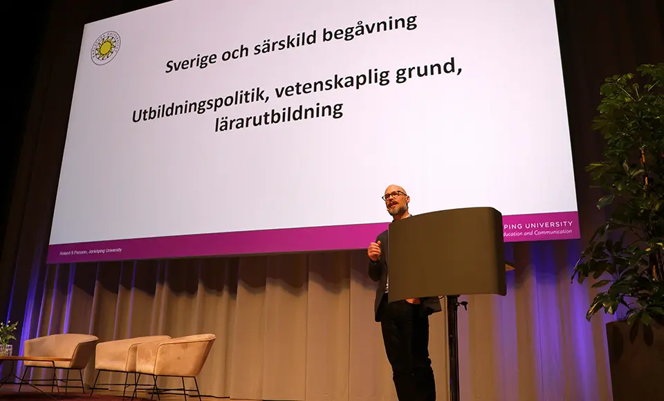 Jesper Boesen står bakom ett talarbord och bakom honom syns en presentation där det står Sverige och särskild begåvning, utbildningspolitik, vetenskaplig grund och lärarutbildning.
