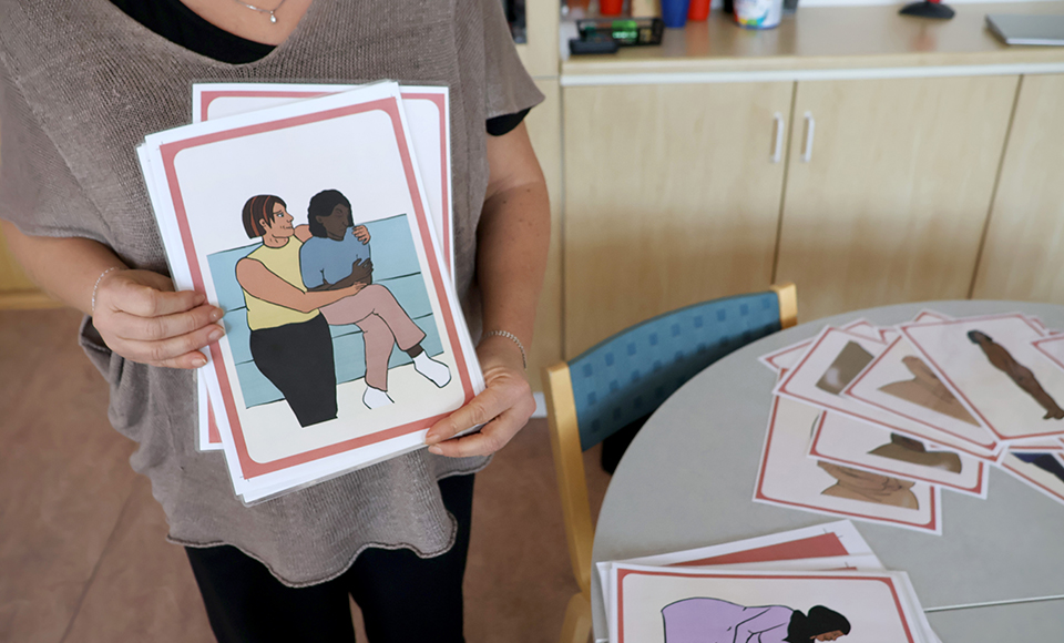 En person håller upp en bild på två personer som sitter bredvid varandra i en soffa. Den ena personer vänder sig bort.