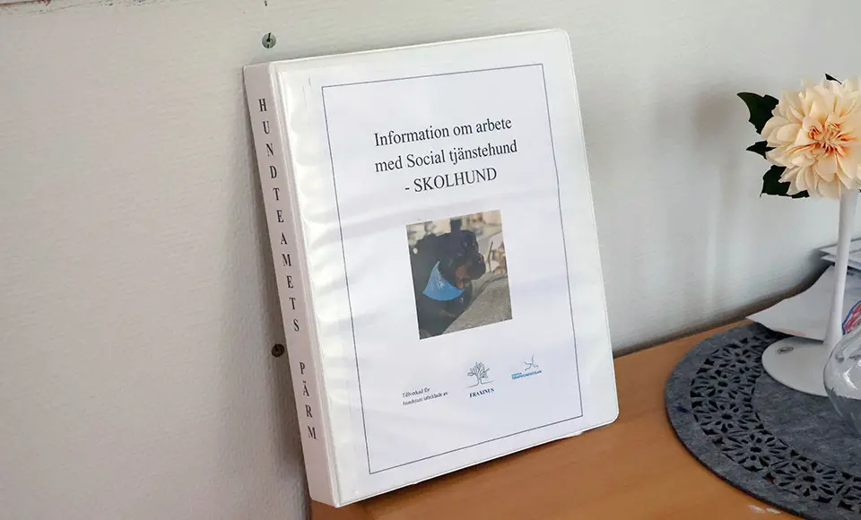 En pärm där det står "Information om arbete med social tjänstehund - skolhund"