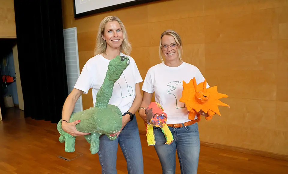 Maria Fråhn och Charlotta Wärnbring håller i varsin dinosaurie i paper mache.