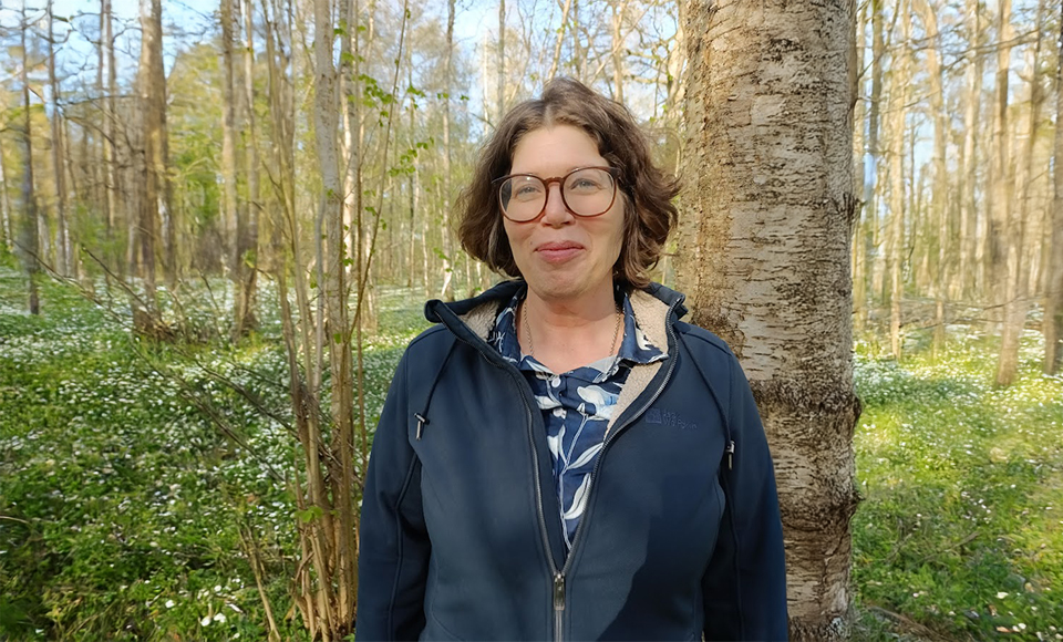 Porträttbild på Anne Liljeblad som står vid en vitsippsäng.