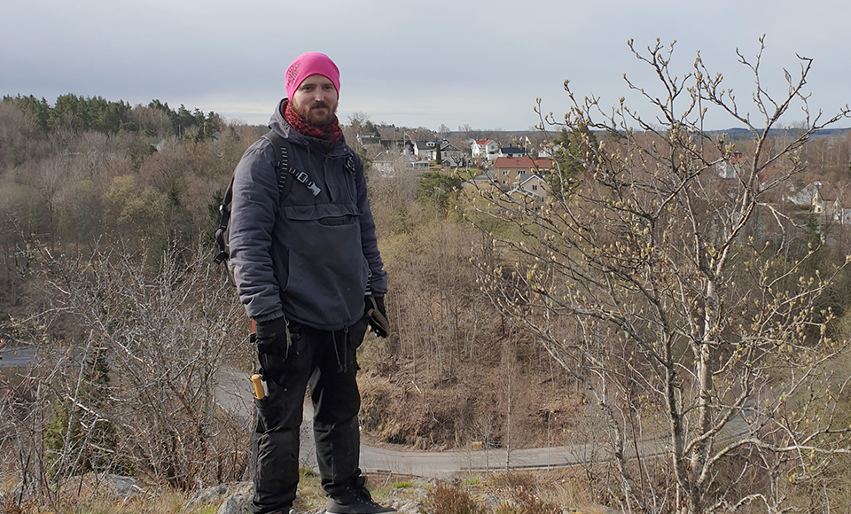 Linus Ögren står vid en utsiktsplats. I bakgrunden syns ett berg med hus.