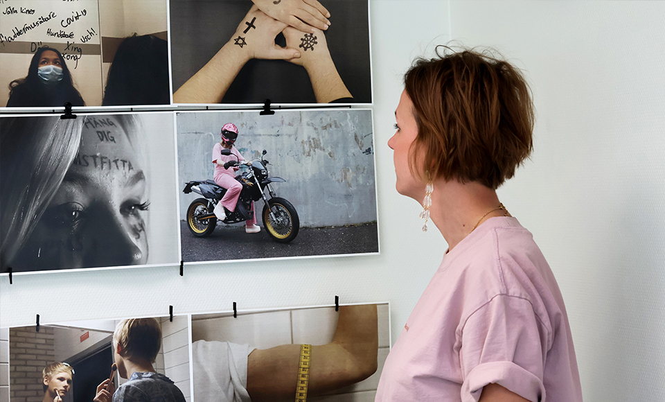 Foto på Emma som står och tittar på en fotovägg med foton från tidigare Normstormutställningar.