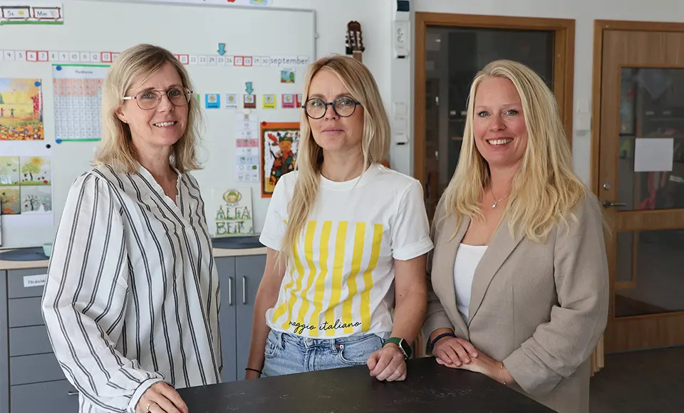 Christina, Malin och Caroline i förskoleklass på Fagerslättsskolan står bredvid varandra vid ett bord.
