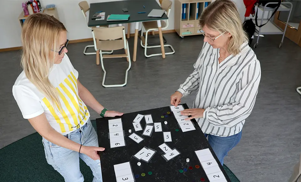 Malin och Christina står vid ett bord och övar på siffror.