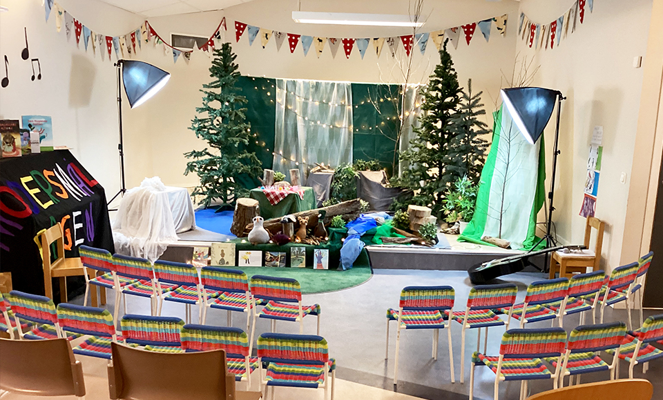 Ett rum med en scen. På scenen är det en skog uppbyggd. Vid scenen står stolar utställda.