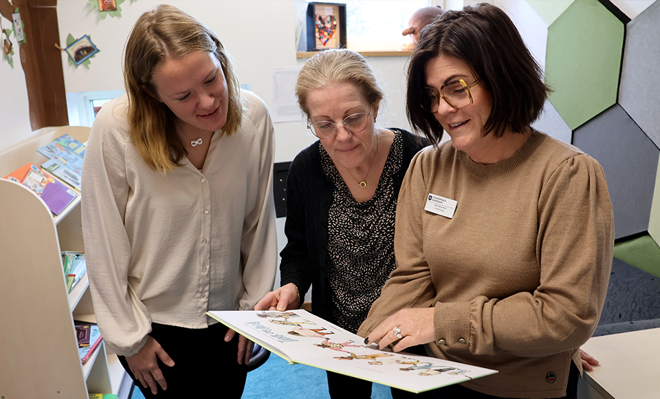 Katrin, Gunilla och Maria läser ur en bok.