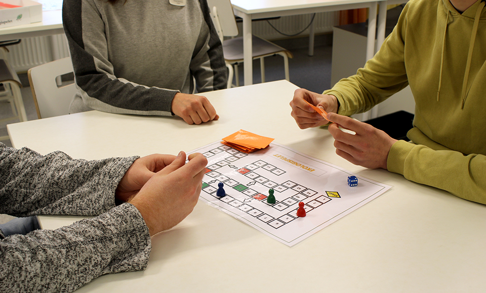 Tre personer sitter vid ett bord och spelar Ekologispelet.