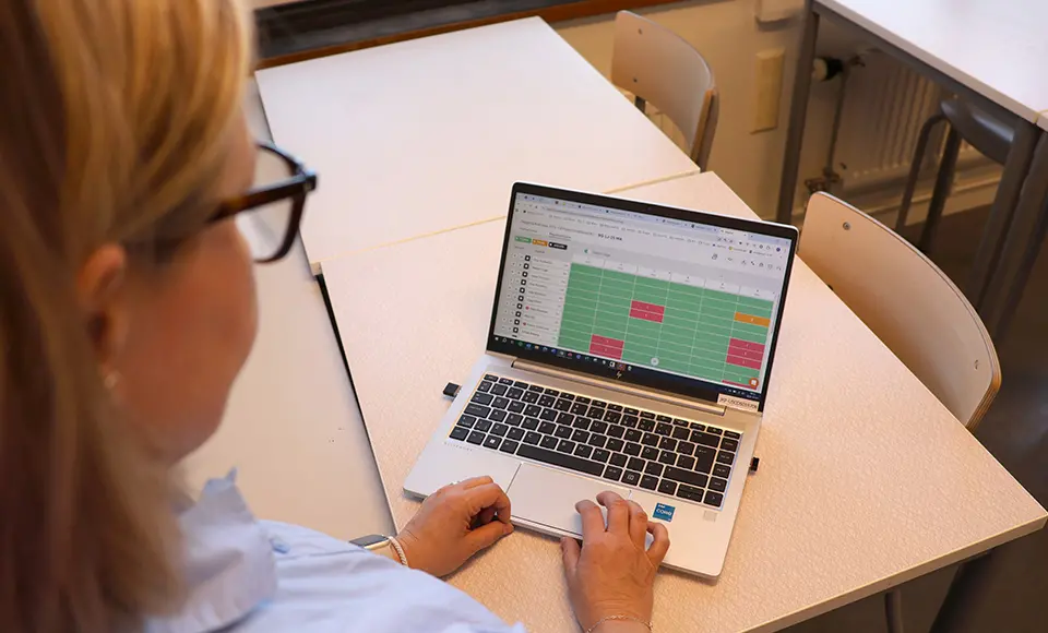 En person står och tittar på en datorskärm där det är markerade gröna, röda och gula fält.