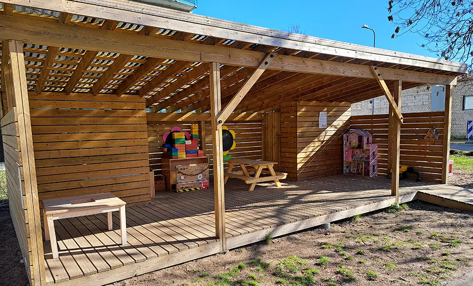 Uteklassrum med tak, bord, bänkar och material.