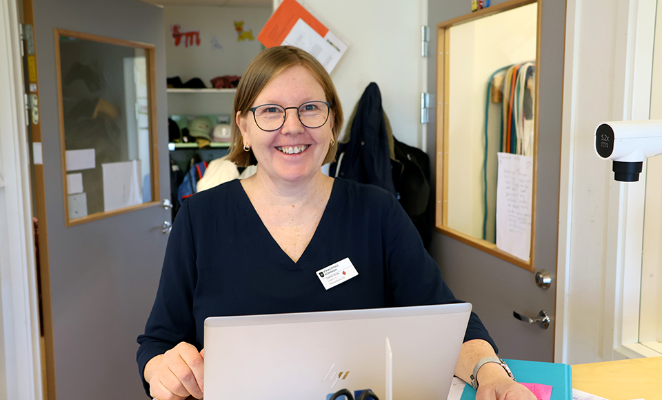Annette Berlin står vid ett ståbord och har en laptop framför sig.